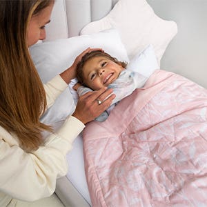 mom putting daughter to sleep with toddler-bed weighted blanket
